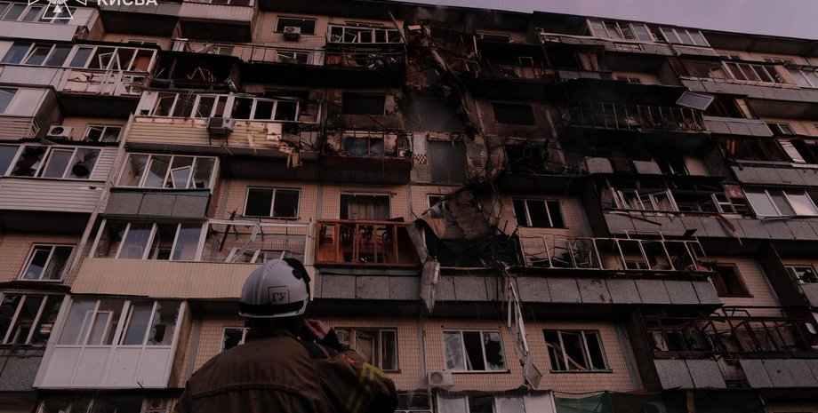 Рятувальник дивиться на будівлю, що зазнала пошкоджень від російської атаки | Фото: ДСНС Напад на Київ: Зеленський повідомив про сплановану атаку — подробиці | INFBusiness